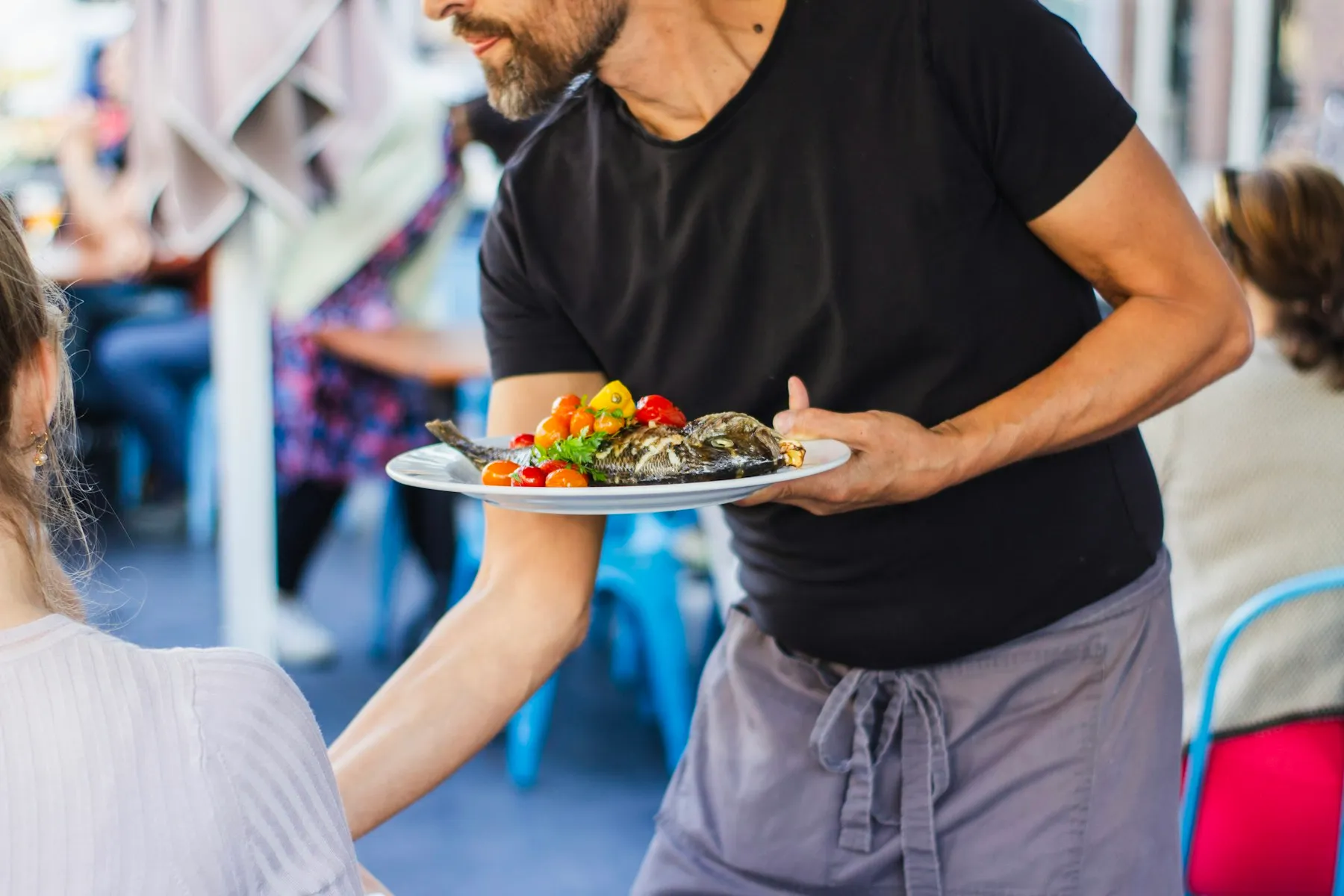 Serveur apportant une assiette en terrasse de restaurant